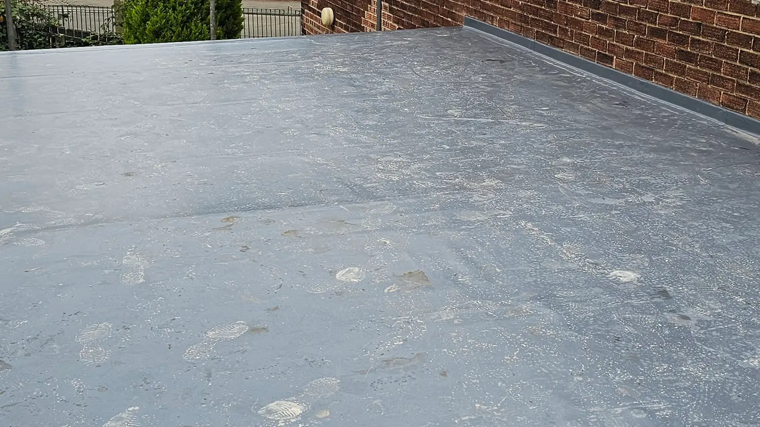Grey single ply flat roof on a brick home, photographed by Sureseal in early November