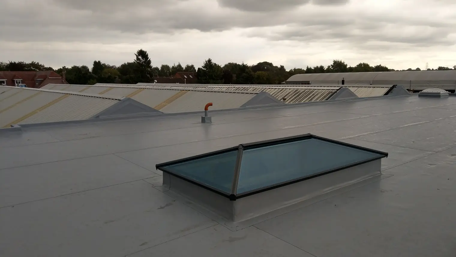 Grey single ply roof with a glazed roof lantern on a single-storey extension