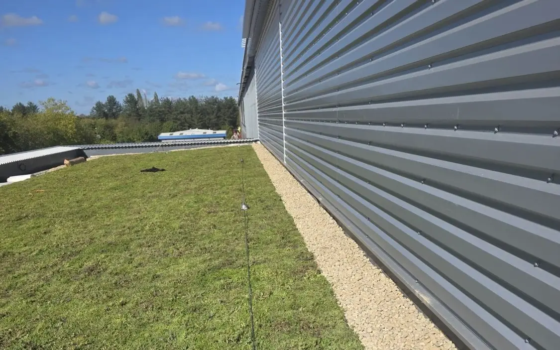 Green roof with a pebble border running along the grey cladding of a commercial building